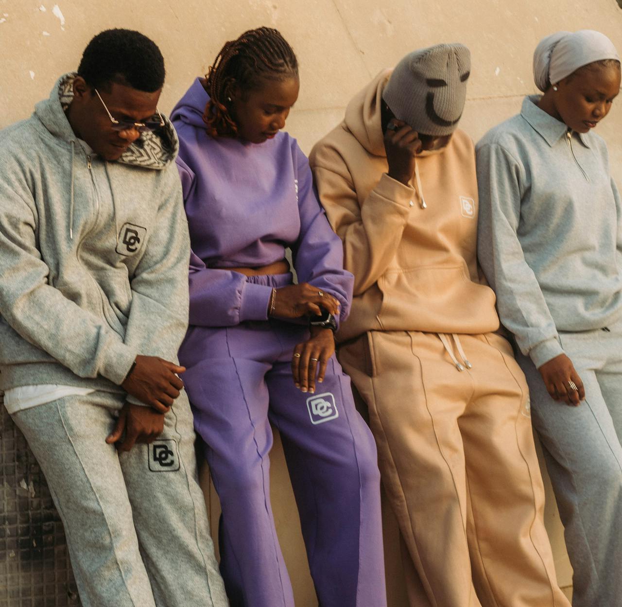 gallery-02 A group of adults in trendy, colorful tracksuits leaning against a wall outdoors.